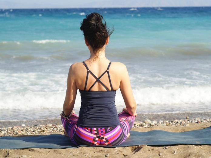 En kvinde sidder på stranden og mediterer