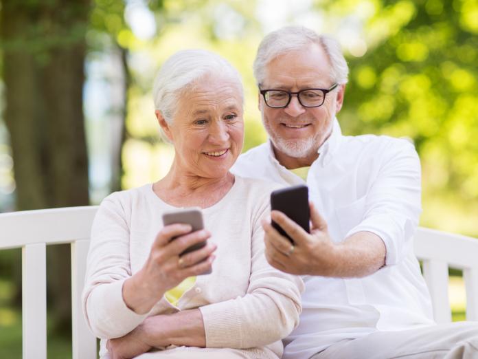 To personer sidder og kigger på deres mobiltelefoner sammen. 